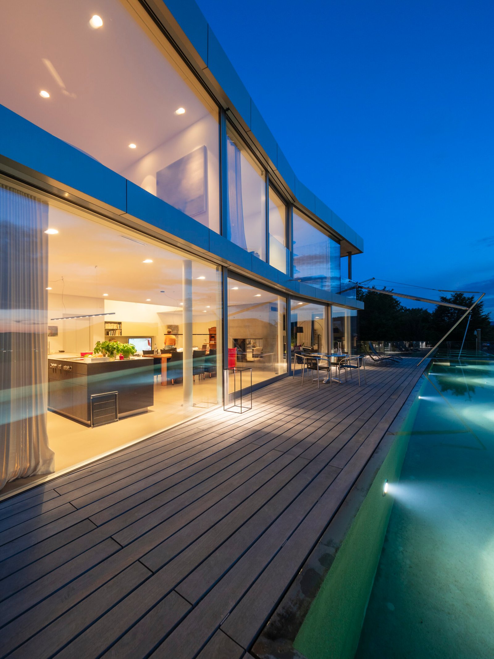 Switzerland, lighted modern villa at dusk with terrace and pool in the foreground